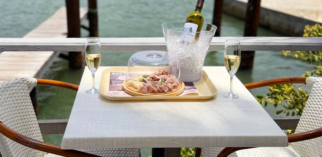 A charcuterie board and chilled wine set on a lagoon side table at La Sucriere, Simpson Bay